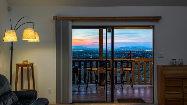 Sala de estar con sofá, una mesa de centro y vistas a un balcón con sillas y baranda de madera.