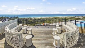 A deck with a curved white seating area and a view of the ocean.
