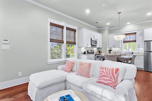A modern kitchen with white cabinets, stainless steel appliances, and a dining area with a table and chairs. - Carriage House-2 bikes-300 Yards to Frog Pool! (Santa Rosa Beach)