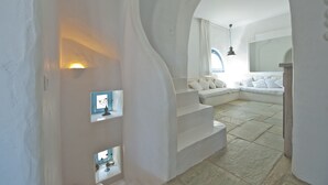 A modern interior with a white staircase leading to a seating area, a large mirror, and a stone floor. - Villa-waterfront, infinity pool-splendid views-luxurious amenities  (PAROS)
