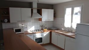 Una cocina moderna con armarios blancos, estufa a gas, microondas y refrigerador.