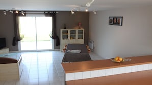 Habitación de hotel moderna con zona de comedor, televisor y vistas a través de la puerta de vidrio.