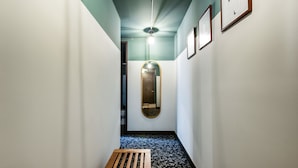 A narrow hallway with a wooden bench, a ceiling fan, and framed artwork on the walls. - Socialtel Parque 93 Bogota (Bogotá)