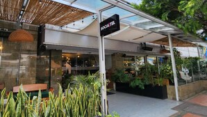 A modern building with a sign reading "SOCIA TEL" and a covered outdoor area with plants and seating. - Socialtel Parque 93 Bogota (Bogotá)