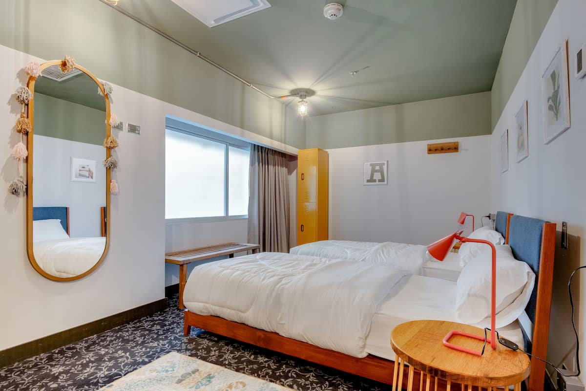 Et hotelværelse med en stor seng, et rundt træsidebord, et spejl og en loftsvifte.