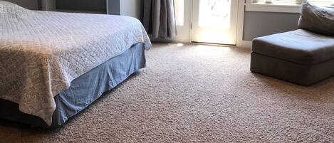 Ein Schlafzimmer mit Bett, Stuhl, Deckenventilator, Fenster und Tür.