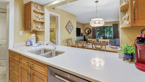 Una cucina moderna con una grande isola, elettrodomestici in acciaio inossidabile, mobili in legno e un'area pranzo con tavolo e sedie.