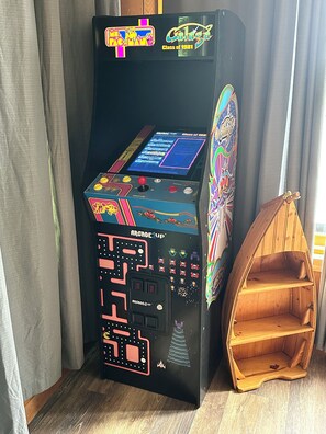 A vintage arcade machine labeled 'Arcade Up' with a colorful design, placed next to a wooden shelf.