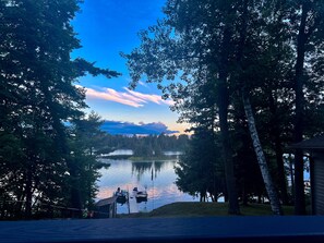 A lakeside view with a dock and boats, surrounded by trees and a clear sky.