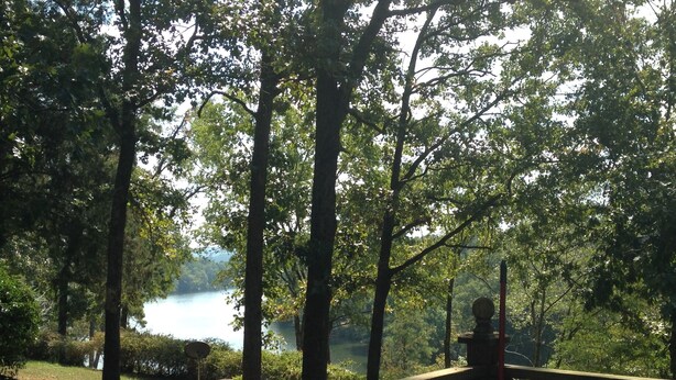 Une terrasse en bois avec des bancs, donnant sur un lac entouré d’arbres.