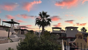 Ein Resort mit einer Palme, Sitzgelegenheiten im Freien und einem Sonnenuntergangshimmel.