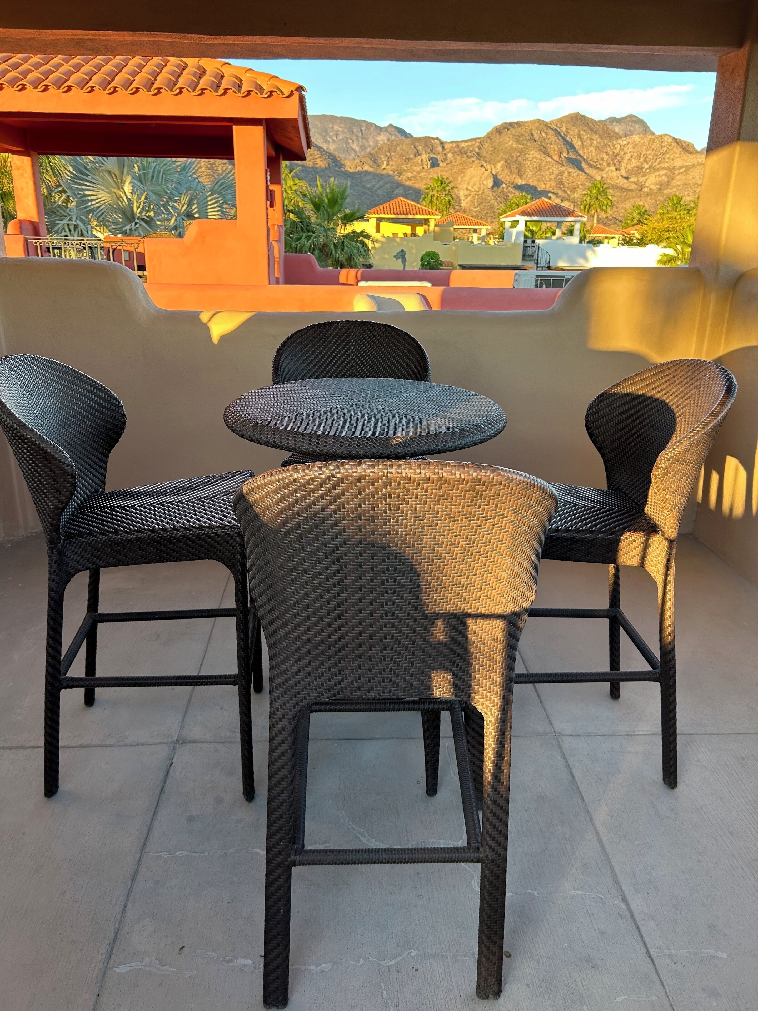 A patio with wicker furniture and a view of mountains.