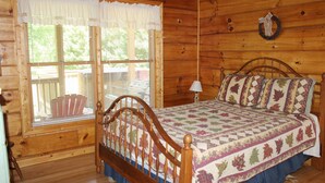 Camera da letto in una baita di legno con un letto, una finestra con persiane e una ghirlanda appesa al muro.