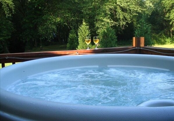 Relax in a serene hot tub surrounded by lush greenery on a deck.