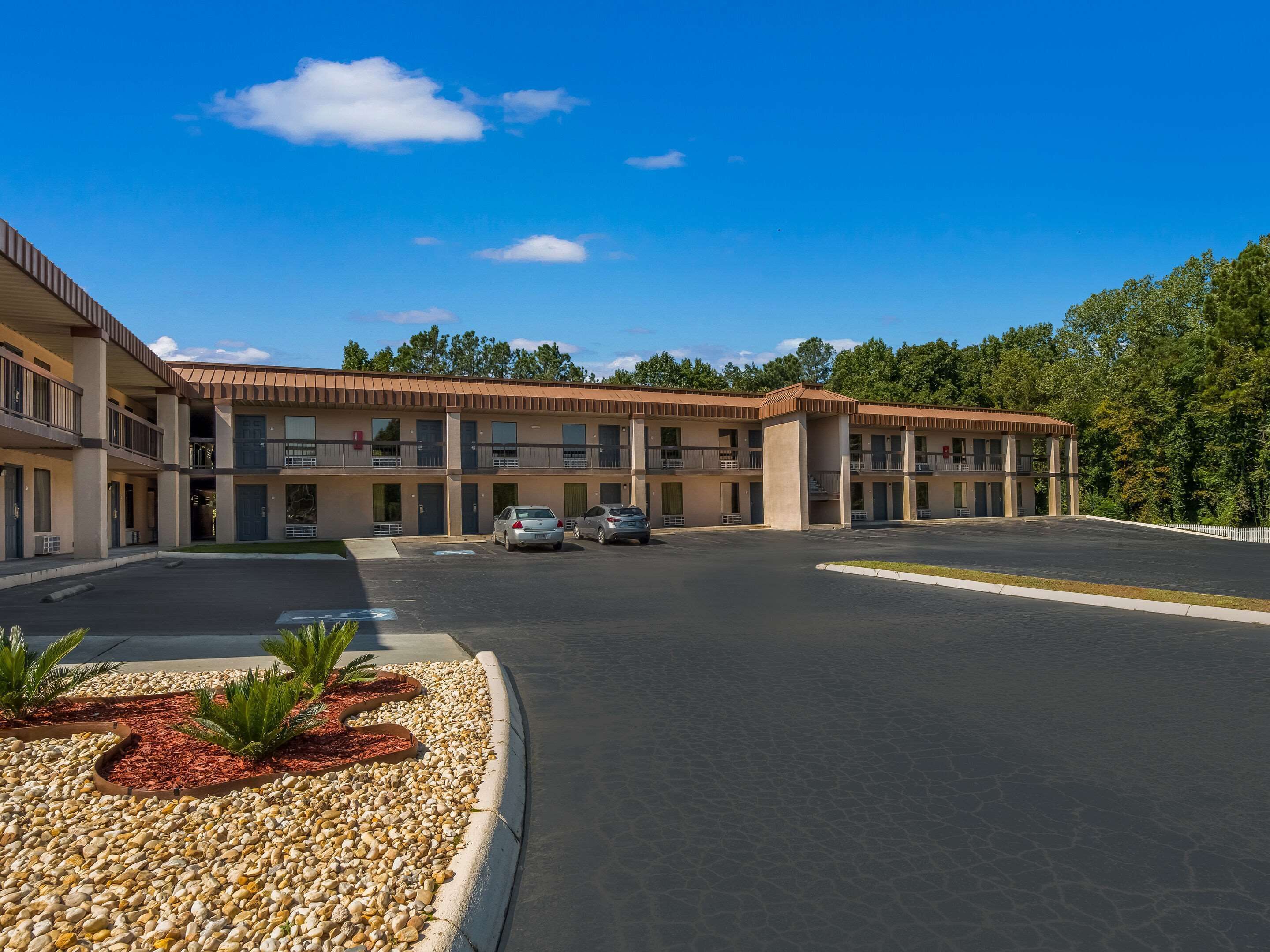 A motel with a central courtyard, multiple balconies, and a parking area.