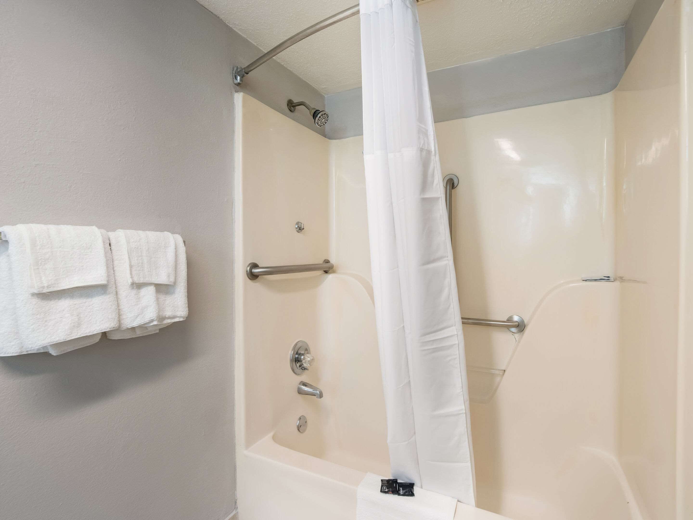 Une salle de bain avec une baignoire, une douche avec un rideau et un porte-serviettes avec des serviettes.