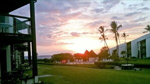 A resort with a view of the sunset over the ocean, palm trees, and a well-maintained lawn. -  #239 Steps to Kamaole III Beach,  New Kitchen 'Solid Gold Value' Maui Revealed (Kihei)