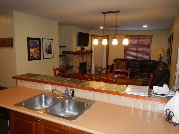 A kitchen with a double sink, a stone fireplace, and a dining area with a table and chairs. - Great Condo.3 night Minimum (Salt Lake City)