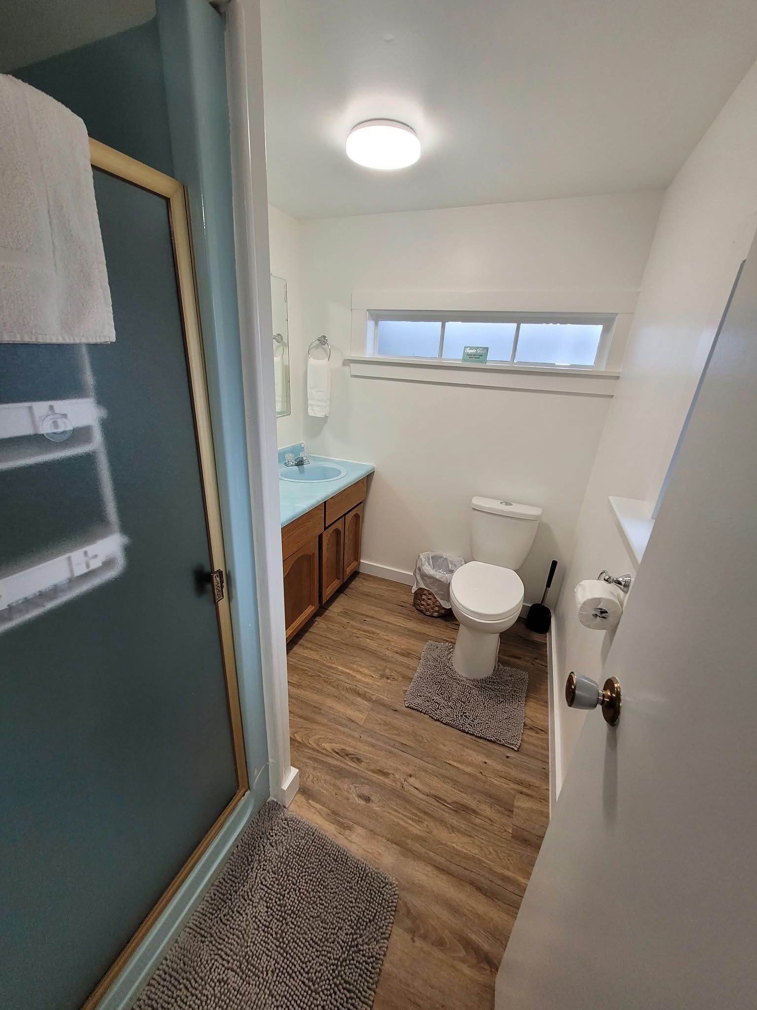 A bathroom with a toilet, sink, and window.