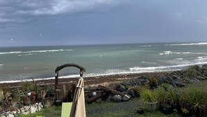 A coastal view with a wooden structure, rocky shoreline, and potted plants. - Seaside Beach Croft Cabin (Qualicum Beach)