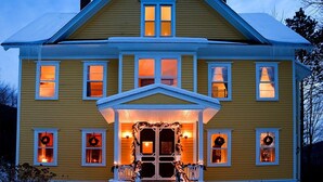A two-story yellow house with a front porch, multiple windows, and a chimney. - Historic 6-bedroom manor next to Beaverkill River — sleeps 18, 5 en-suite baths. (East Branch)