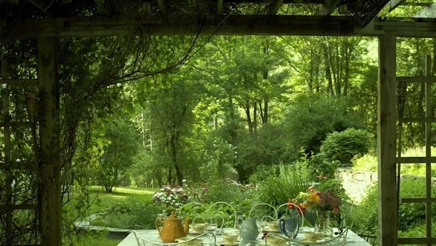 A table set outdoors with a garden view, surrounded by wooden pergola structures. - Historic 6-bedroom manor next to Beaverkill River — sleeps 18, 5 en-suite baths. (East Branch)