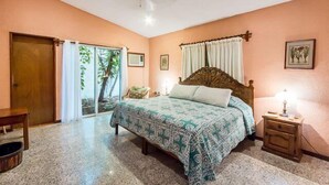 Una camera da letto con un letto, un comodino, una porta in legno e una finestra con tende.