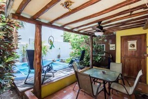 Un patio cubierto con piscina, mobiliario exterior y plantas en macetas.