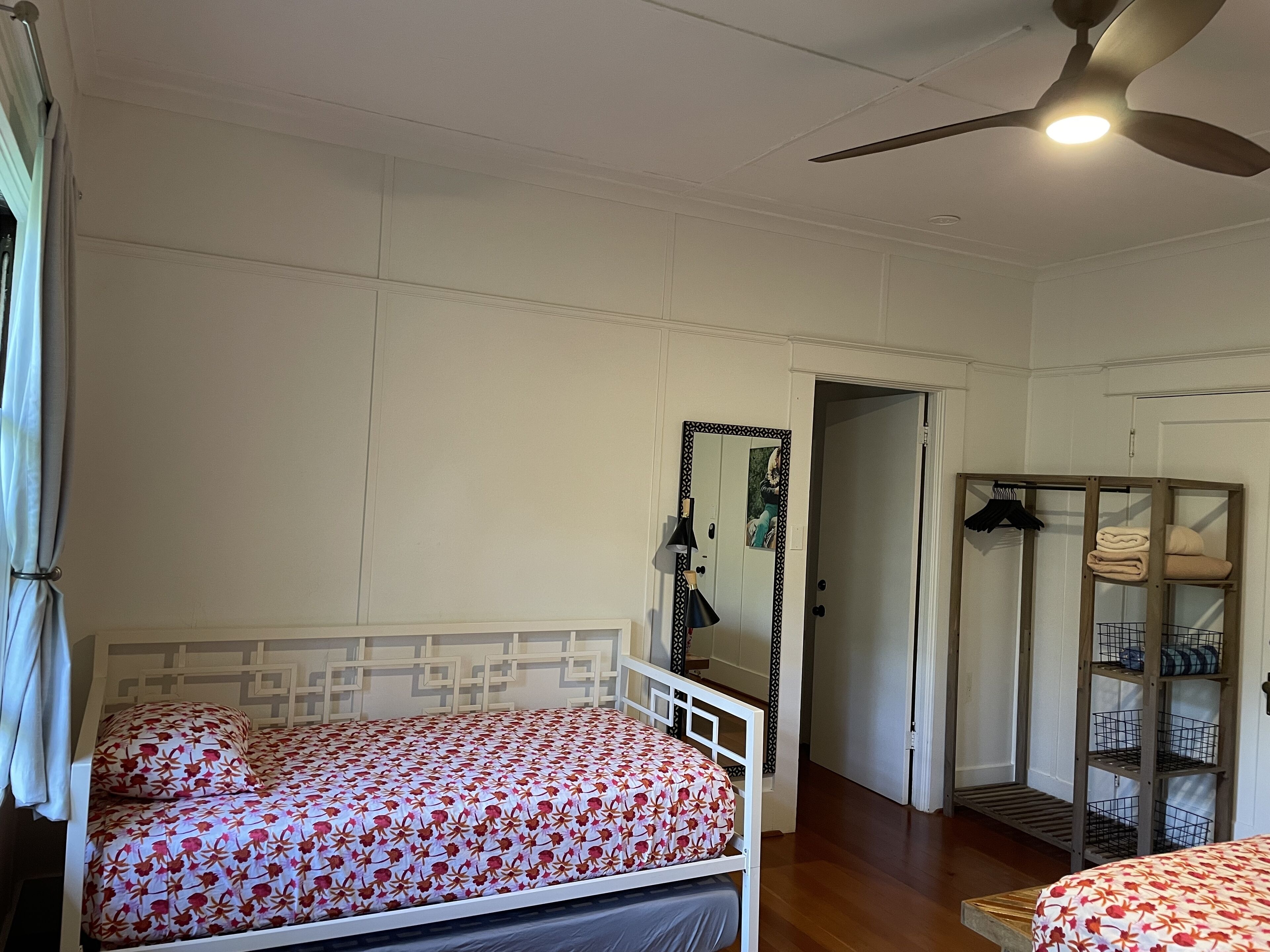 Een slaapkamer met twee bedden, een plafondventilator, een kast en een spiegel.