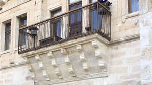 Ein Gebäude mit einer Stein-Fassade, Rundbogenfenstern und einem Balkon mit schmiedeeisernen Geländern.