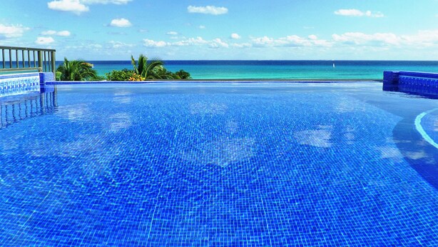 A clear blue infinity pool with a view of the ocean and a clear sky. - Villa Izcalli by PRP (Playa del Carmen)