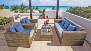 A covered outdoor seating area with wicker furniture and a view of the ocean. - Villa Izcalli by PRP (Playa del Carmen)