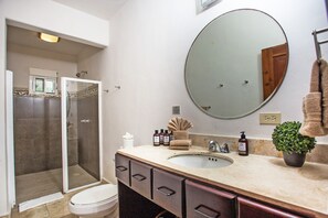 Een badkamer met een grote spiegel, een wastafel en een douchehoek.