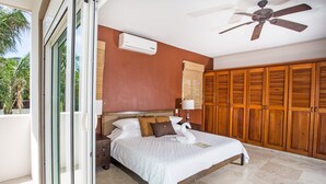 A bedroom with a bed, wooden wardrobe, and a ceiling fan. - Villa Izcalli by PRP (Playa del Carmen)