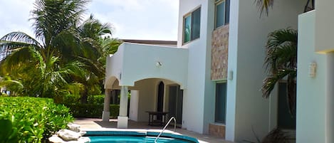 A swimming pool surrounded by a white building with arched windows and a tiled exterior.