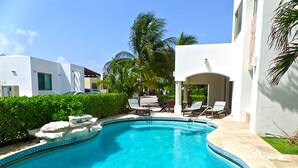 Ein Pool mit Liegestühlen und Palmen.