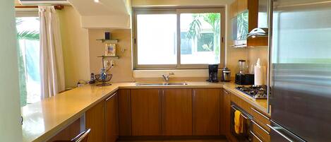 Una cocina moderna con armarios de madera, un refrigerador de acero inoxidable y un ventanal que proporciona luz natural.