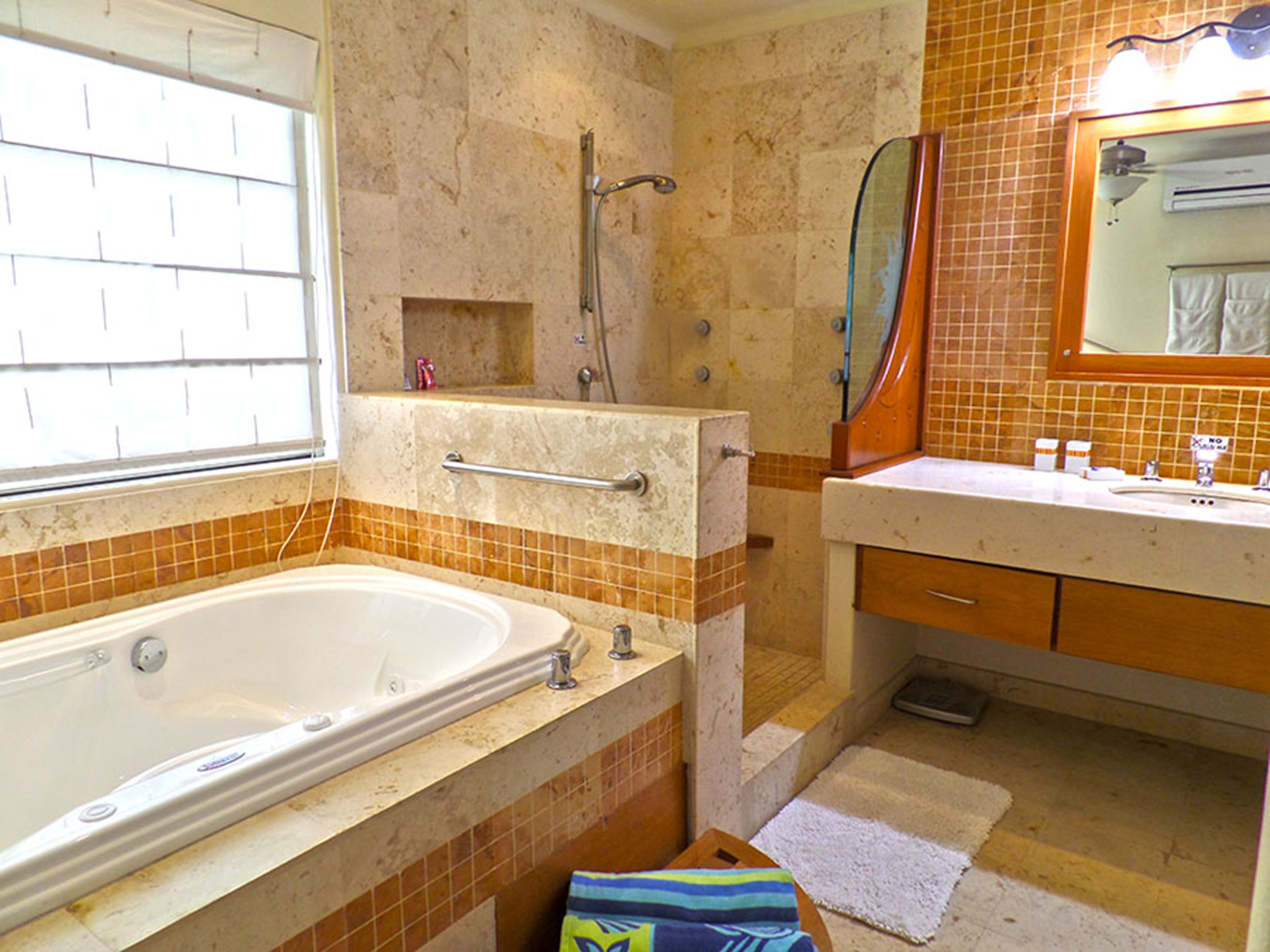 Une salle de bain équipée d’une baignoire, d’une douche, d’un meuble-lavabo avec un miroir et d’un porte-serviettes.