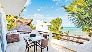 Un balcón con mesa y sillas con vistas a una playa.