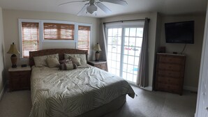 Een slaapkamer met een groot bed, twee nachtkastjes met lampen, een dressoir en een aan de muur bevestigde televisie.