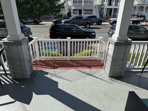A gated entrance with a metal fence, a red pathway, and a white building in the background.