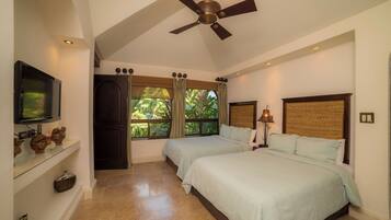 A hotel room with two beds, a television, a ceiling fan, and a large window with curtains.
