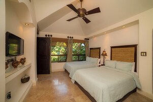 A hotel room with two beds, a television, a ceiling fan, and a large window with curtains.