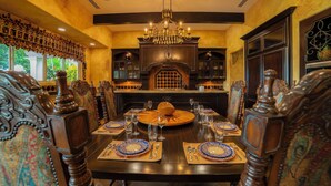 Une salle à manger élégante, dotée d’une grande table ronde, de chaises richement décorées et d’une cheminée ornementale.