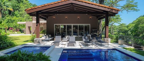 A modern outdoor pool area with a covered seating area and lounge chairs.
