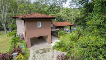 Un bâtiment à deux étages, doté d’un toit en tuiles, entouré d’une végétation luxuriante et agrémenté d’une piscine.