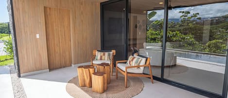 A modern outdoor seating area with wooden furniture and a glass door leading to a balcony.