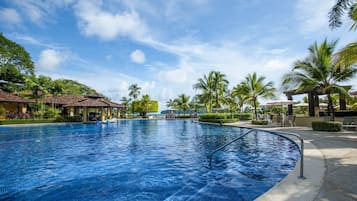 Uma grande piscina ao ar livre com céu azul límpido e palmeiras.