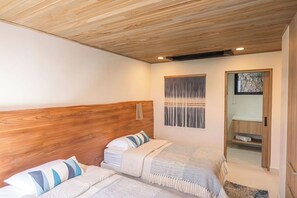 A bedroom with two beds, wooden headboard, a stone wall, and a built-in wardrobe. - Los Suenos Luxury Villas by Stay in Costa Rica (Jacó, Costa Rica)