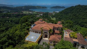 A large house with a spacious driveway and a tennis court. - Los Suenos Luxury Villas by Stay in Costa Rica (Los Sueños)